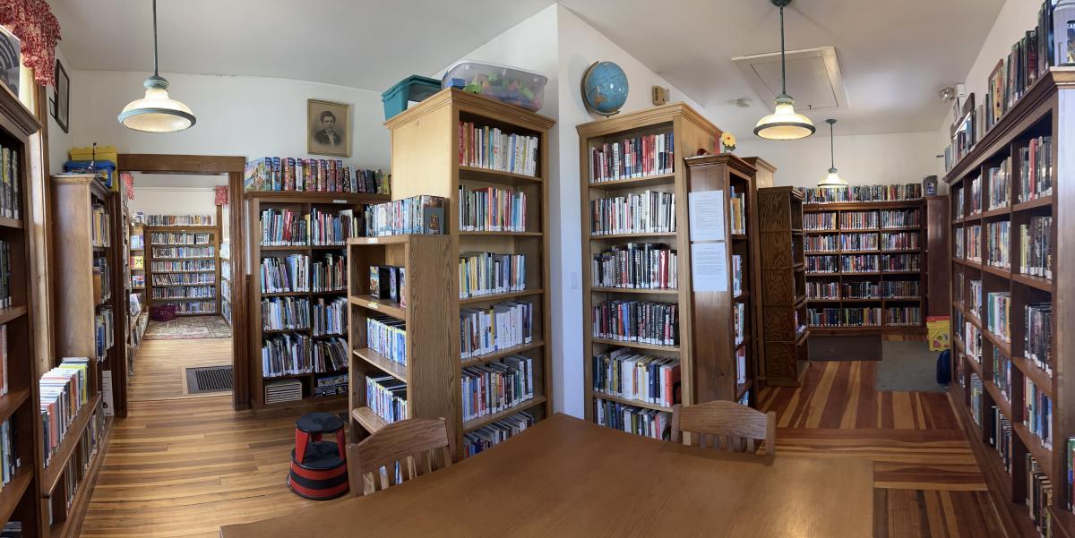 library interior shows wide anle view of books on shelves and craft table